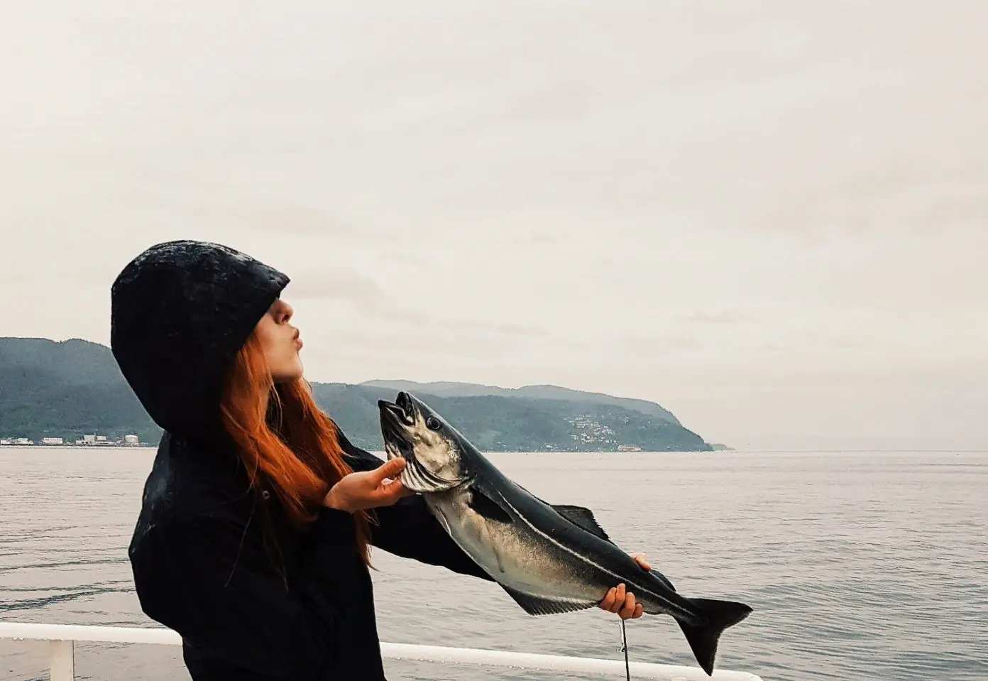 Guest holding a freshly caught fish aboard Ranja on Trondheim Fjord